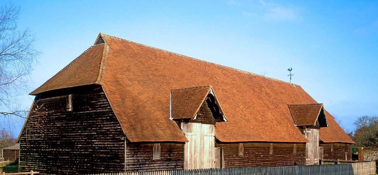 Prior’s Hall Barn in Widdington, Essex, England, featuring a large timber-framed structure with a red tiled roof and traditional rural setting.
