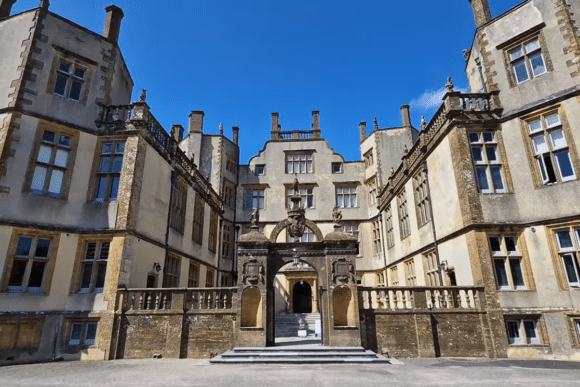 Sherborne Old Castle exterior courtyard with historic stone façade, arched entrance, and Tudor-style architecture under blue sky.