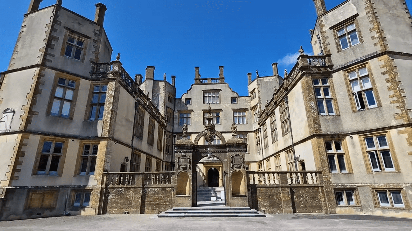 Sherborne Old Castle exterior courtyard with historic stone façade, arched entrance, and Tudor-style architecture under blue sky.