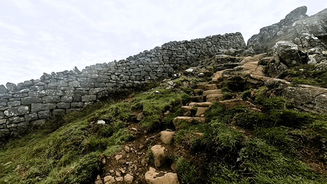 Stone pathway climbing beside Winshields Wall on Hadrian’s Wall, featuring rugged Roman masonry and dramatic countryside terrain in Northumberland, England.