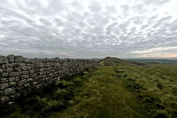 Scenic stretch of Winshields Wall on Hadrian’s Wall featuring ancient Roman stonework, grassy walking paths, and panoramic countryside views under dramatic skies in Northumberland.