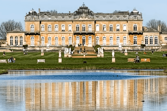 Wrest Park mansion reflected in a tranquil lake, surrounded by formal gardens, statues, and landscaped parkland in Bedfordshire.
