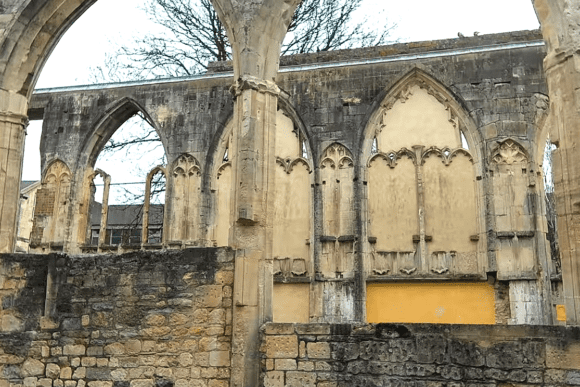 Stone arches and decorative Gothic wall panels of Greyfriars ruins with exposed masonry and pointed arch openings.