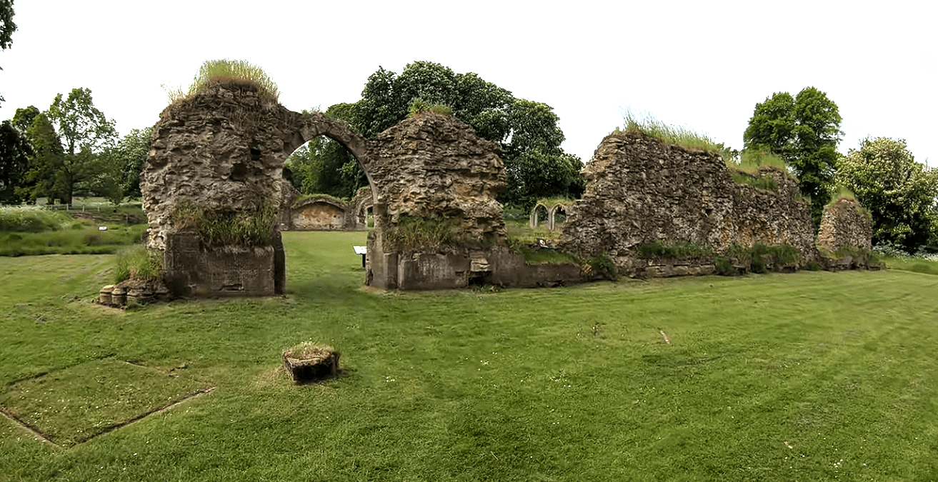 Stone ruins of Hailes Abbey with a surviving pointed arch and grass-covered walls set in a green landscape.