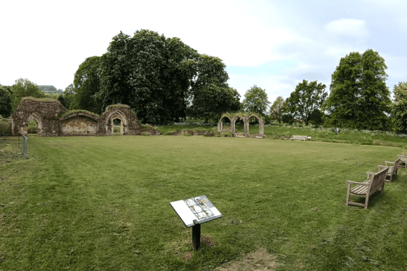 Wide view of Hailes Abbey ruins with scattered stone arches and walls surrounding a grassy open area.