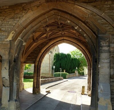 Stone arch passageway of Kingswood Abbey Gatehouse with vaulted ceiling and view to the churchyard outside.